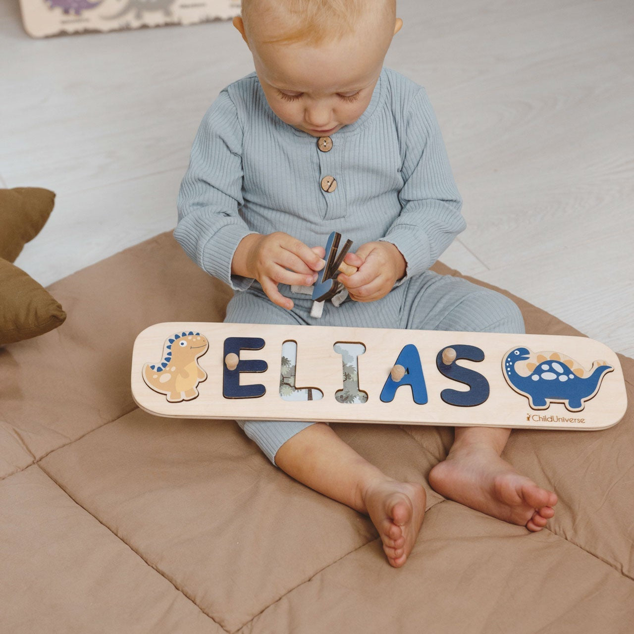 Child playing with a wooden name puzzle on a bed