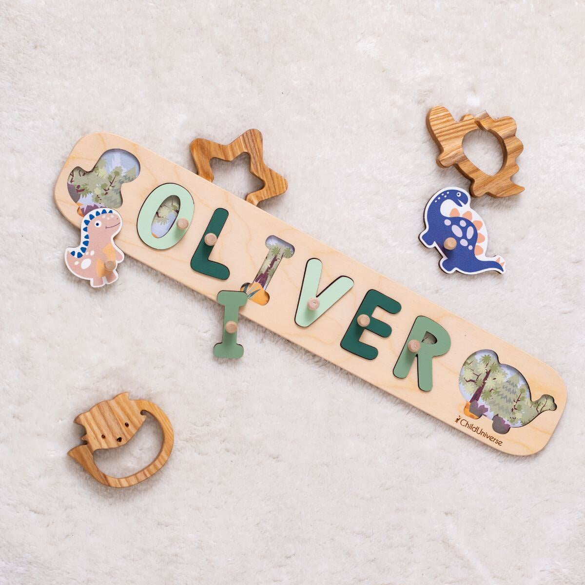 Wooden nameplate with 'OLIVER' and decorative elements on a soft fabric background