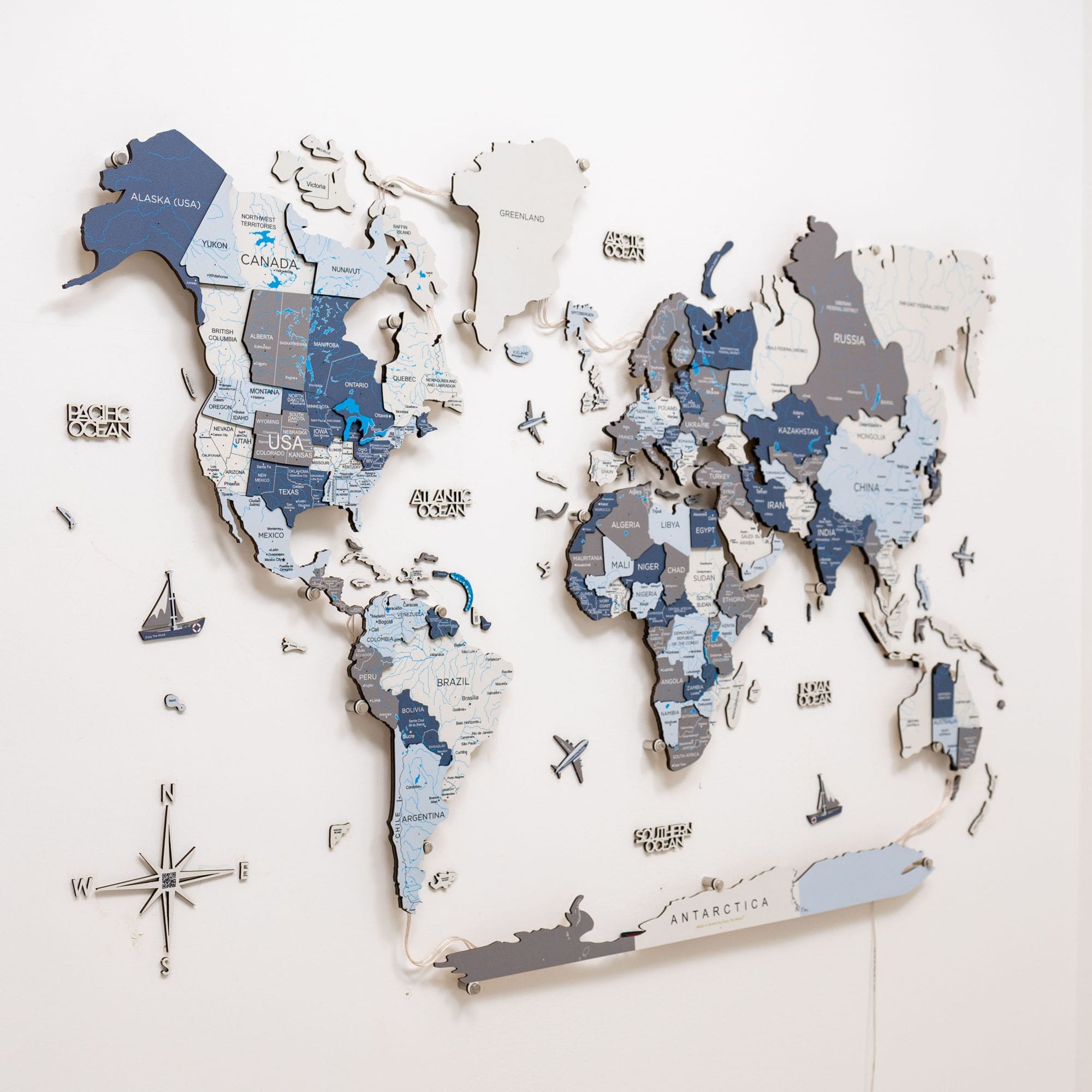 World map puzzle on a white wall with a compass.