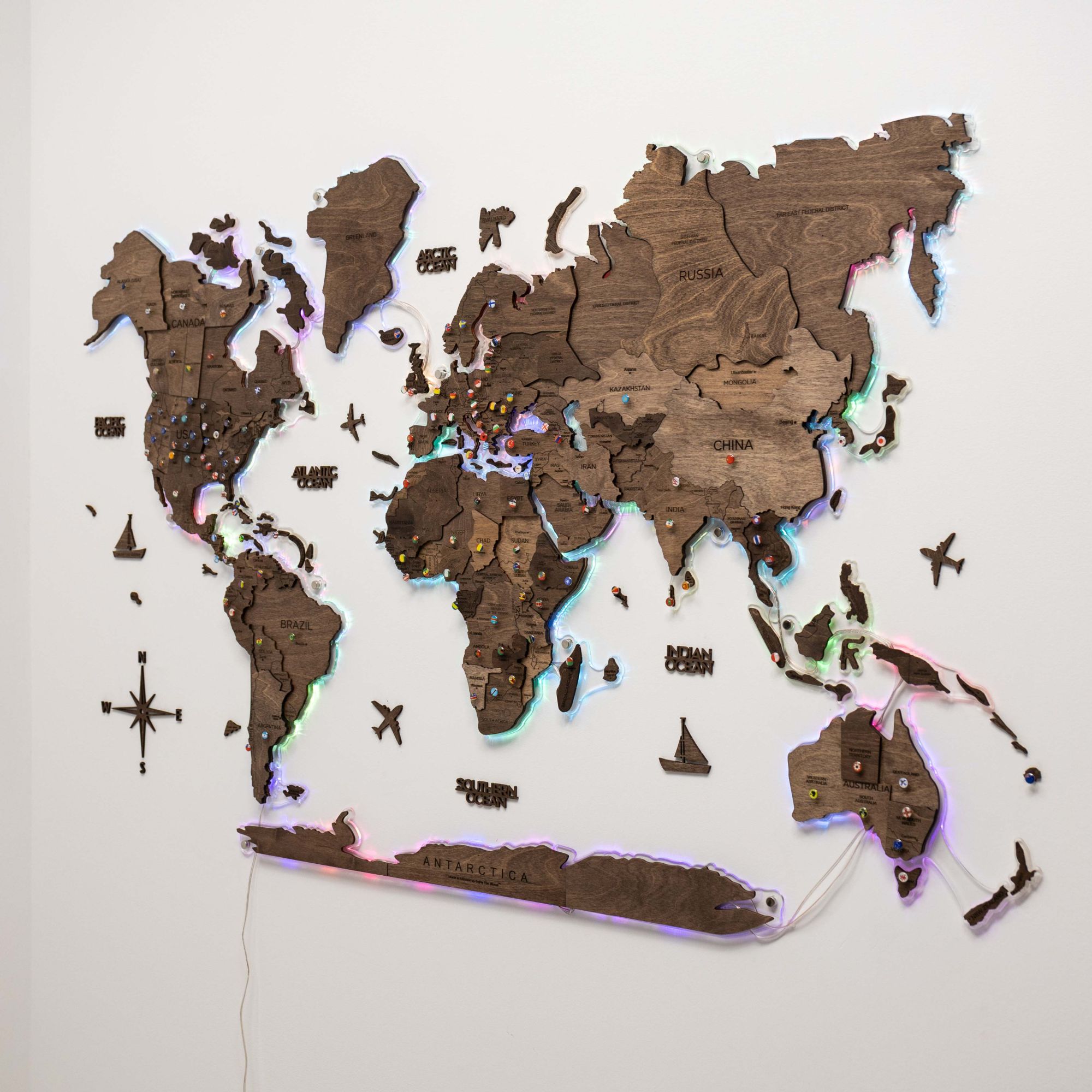 Wooden world map with embedded lights on a white background