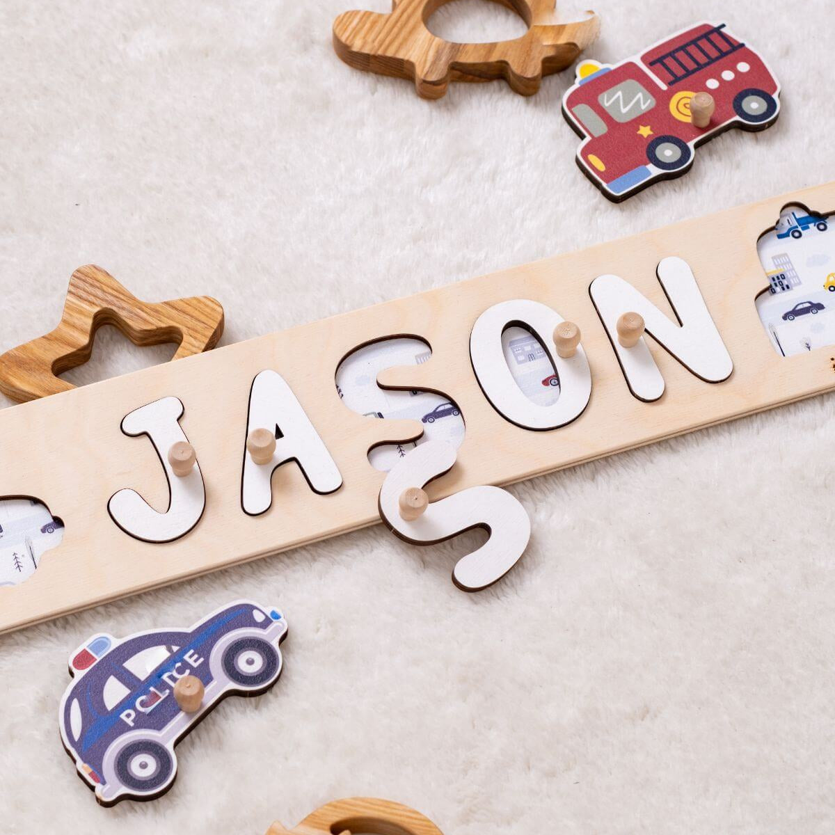 Wooden name puzzle with letters spelling 'JASON' and toy vehicle shapes on a light background