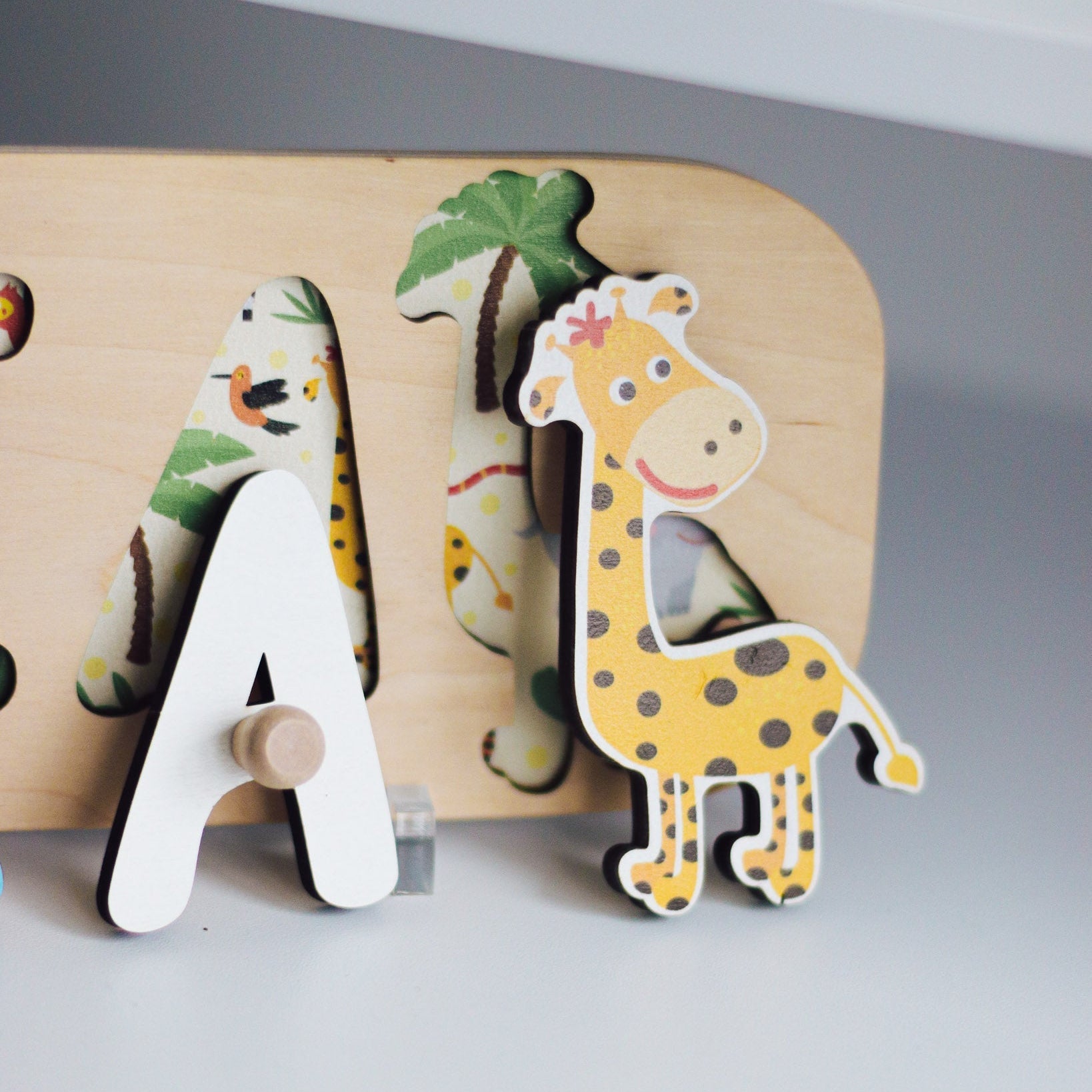 Wooden letter 'A' with a giraffe design on a gray background