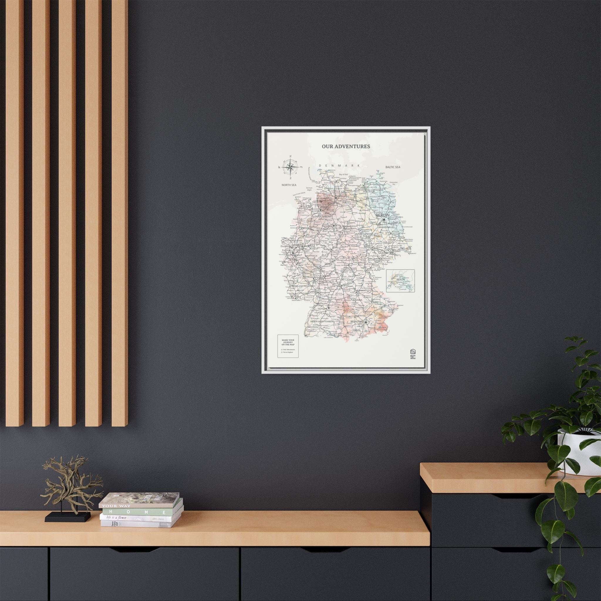 Framed map poster on a dark wall with wooden shelves and plants.