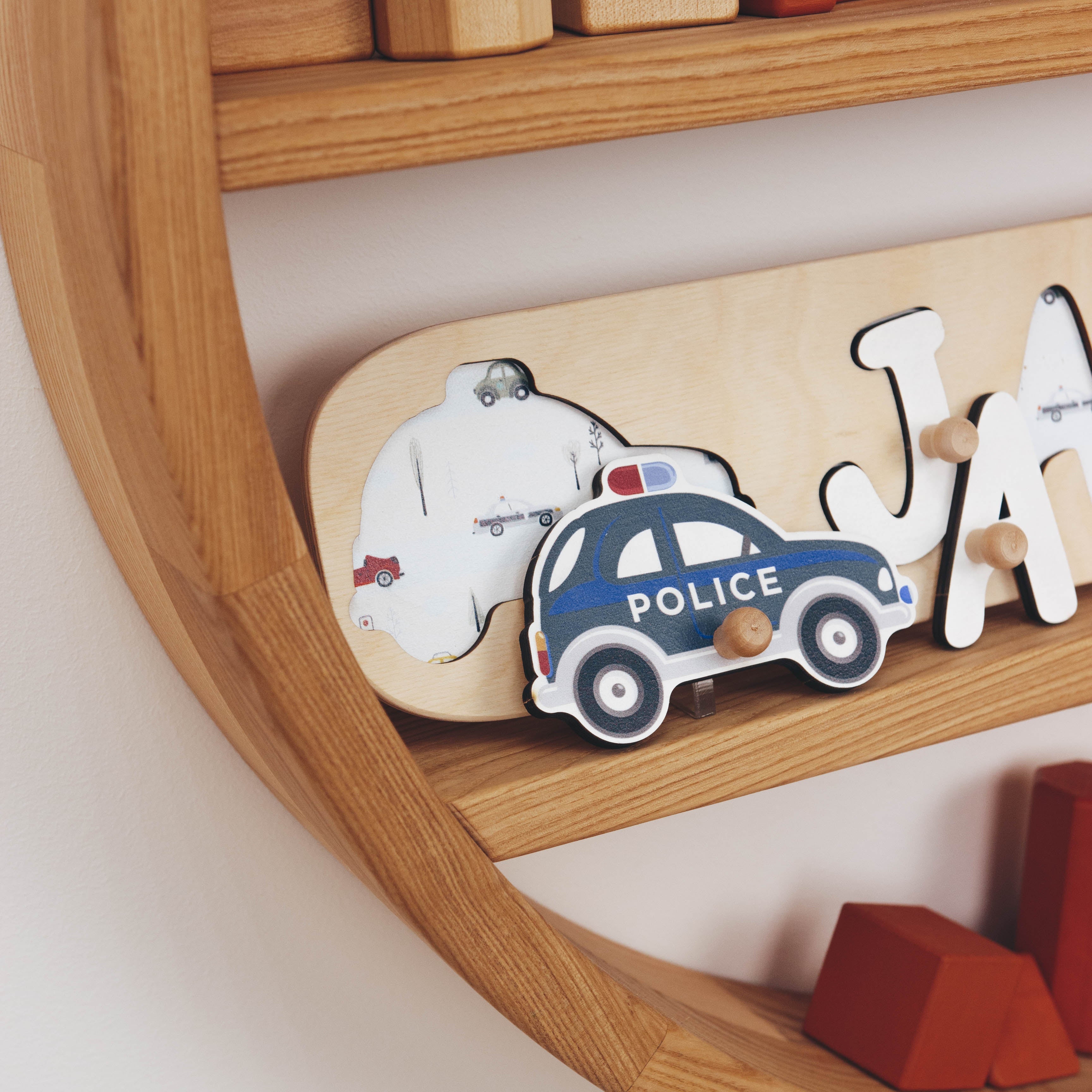 Wooden name puzzle with police car and bear stickers on a wooden shelf.