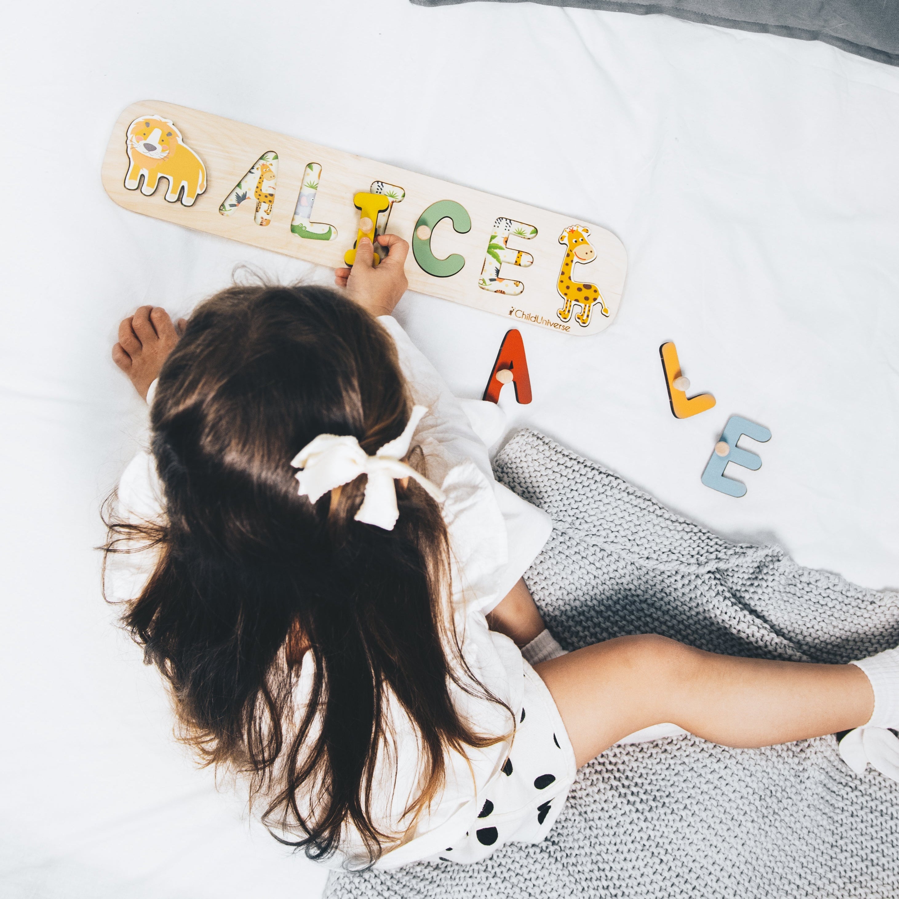 Child playing with alphabet letters on a white surface