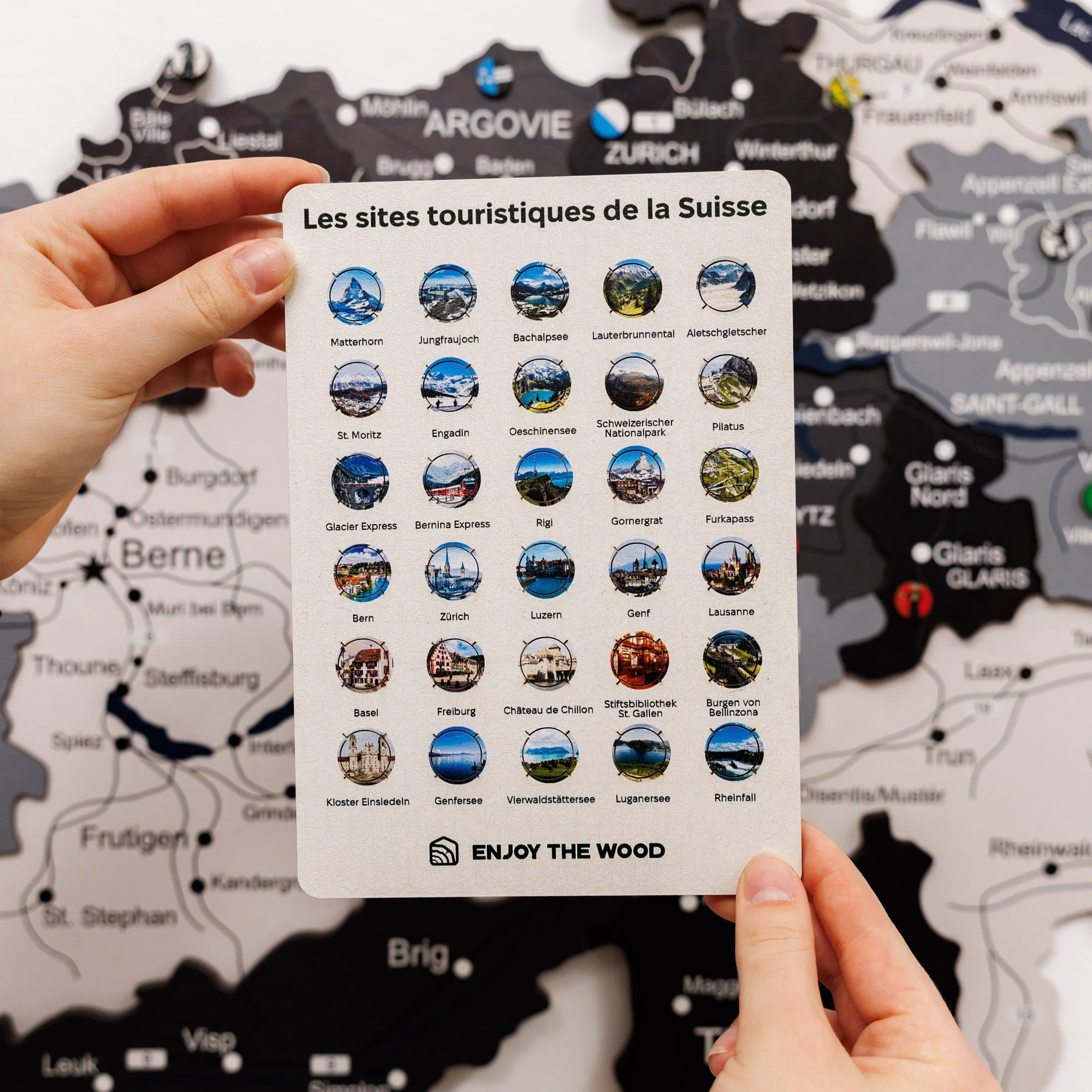 Card with Swiss tourist sites icons held over a map of Switzerland