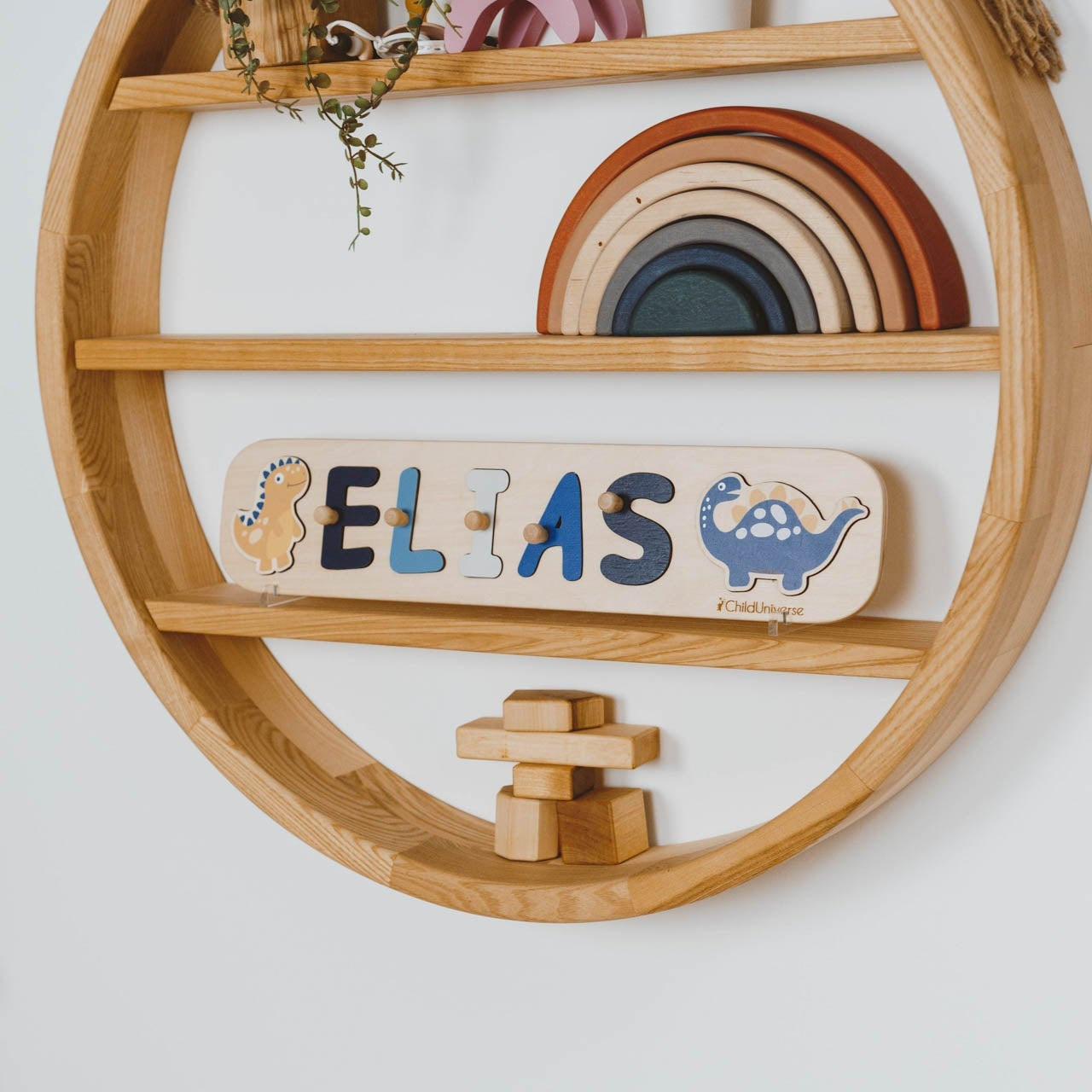 Wooden circular shelf with toys and a nameplate on a white wall