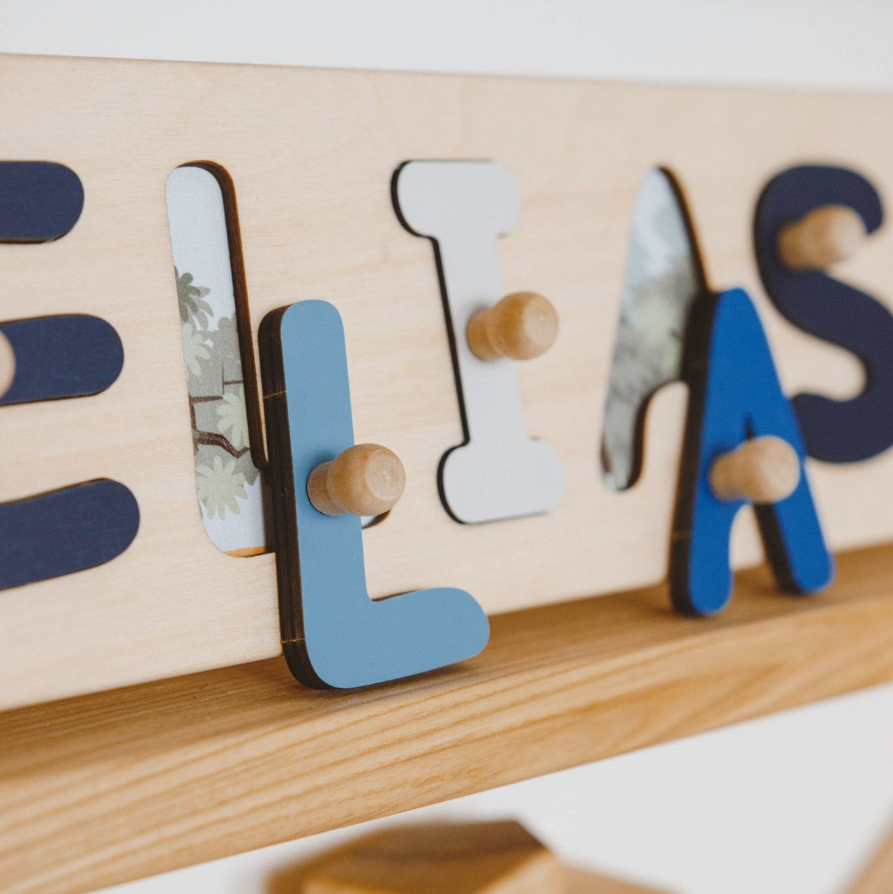 Wooden name puzzle with letters spelling 'ELIAS' on a wooden base.