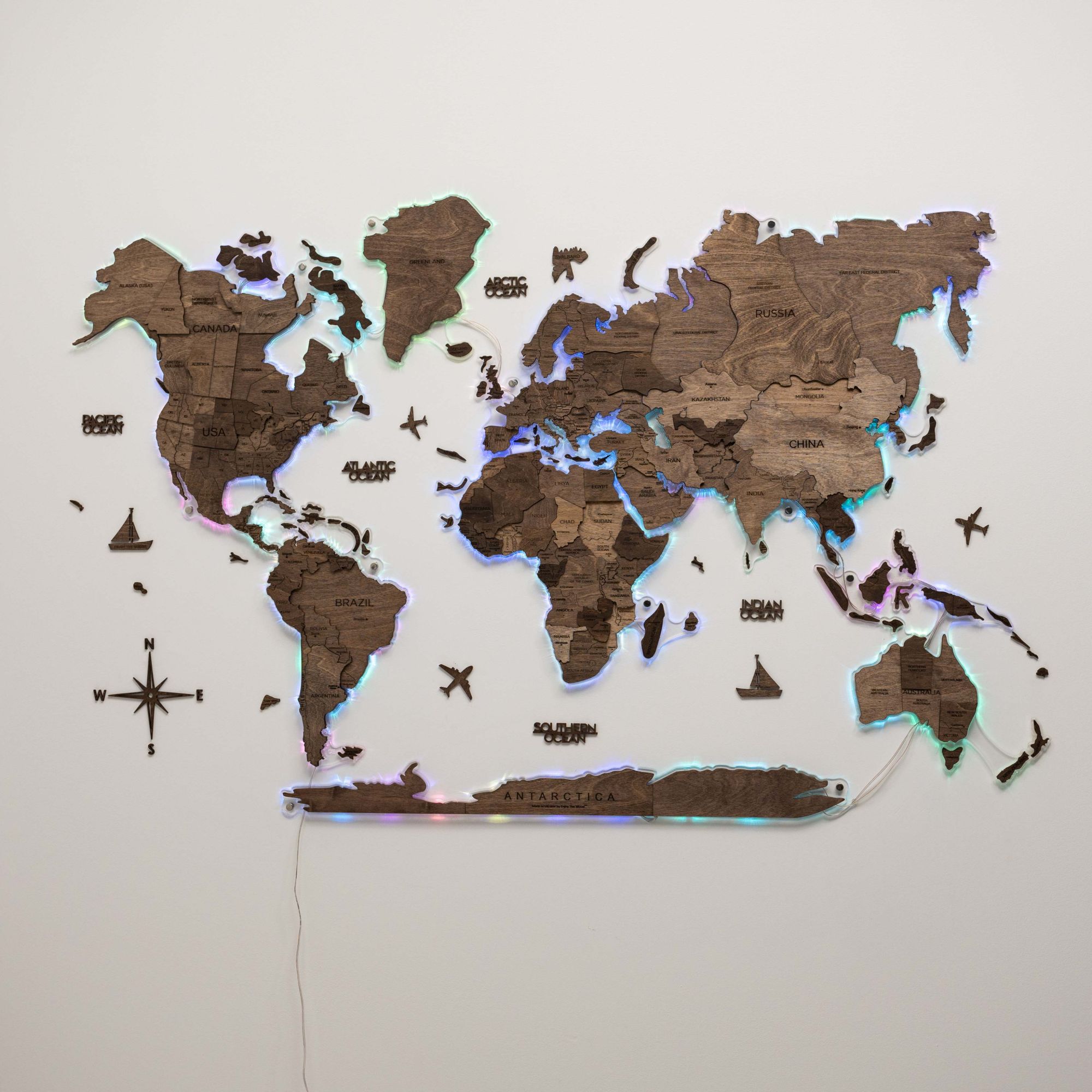 Wooden world map with LED lighting on a white wall